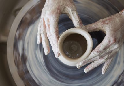 Hands of person making jar out of clay, view from above