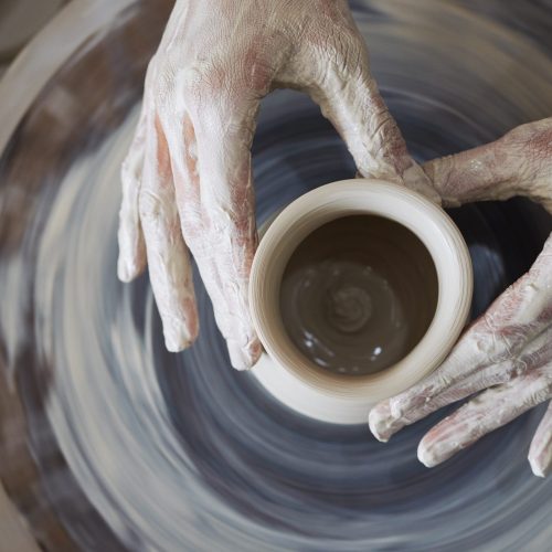 Hands of person making jar out of clay, view from above