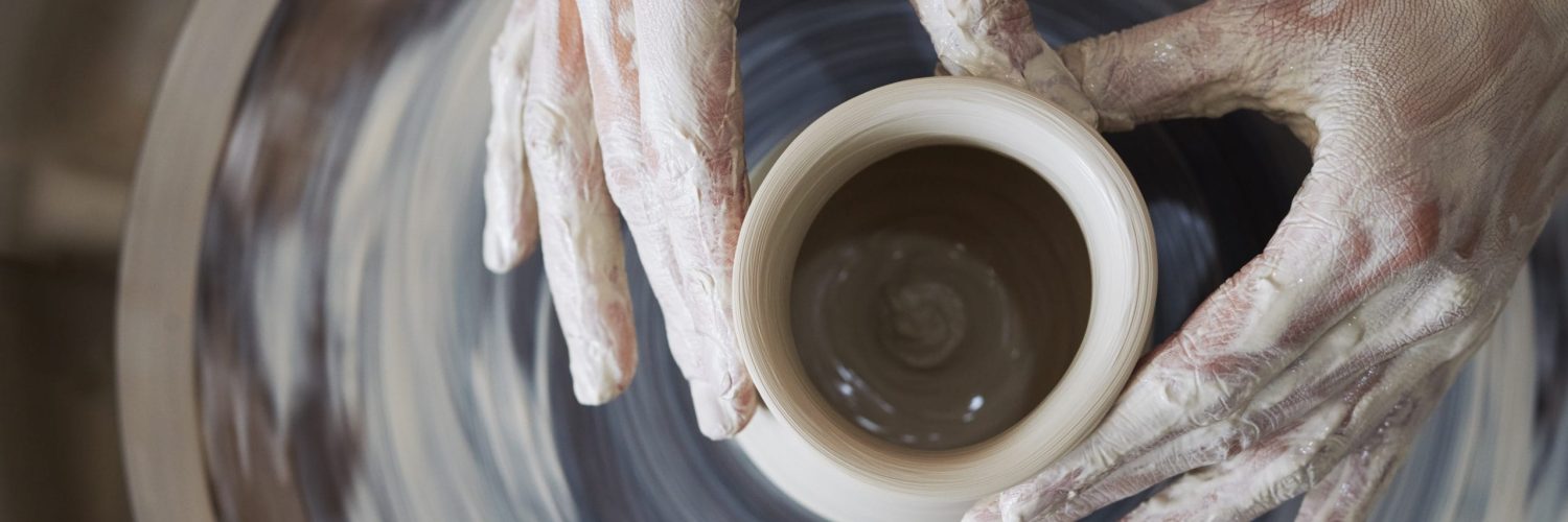 Hands of person making jar out of clay, view from above